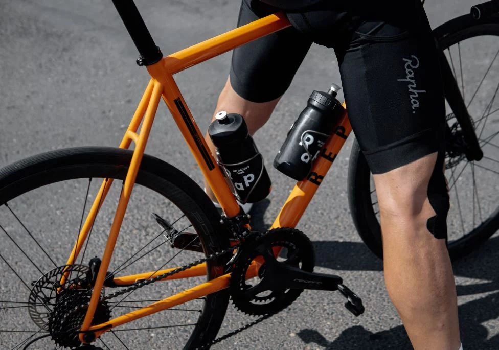 Vélo de course orange et short Rapha.