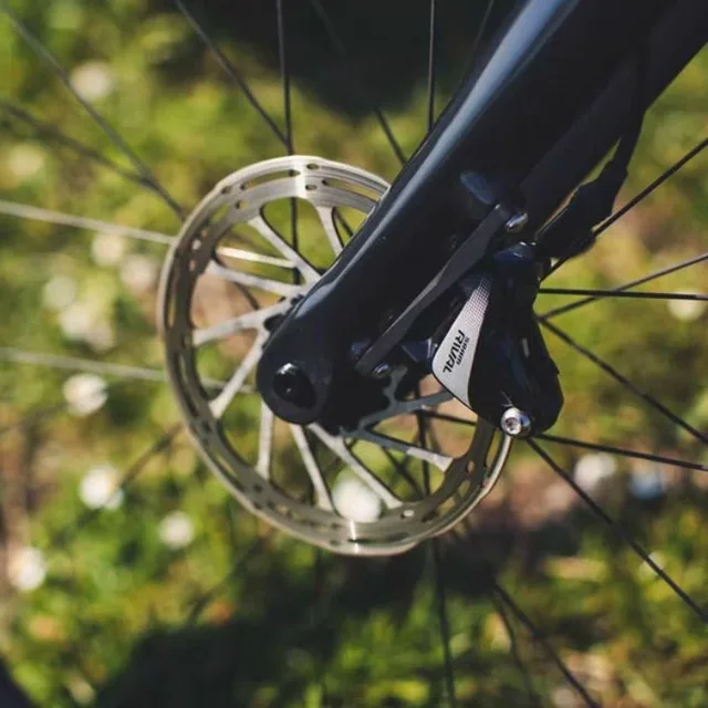 Gros plan sur le frein à disque et le moyeu de la roue avant d'un vélo, dans l'herbe